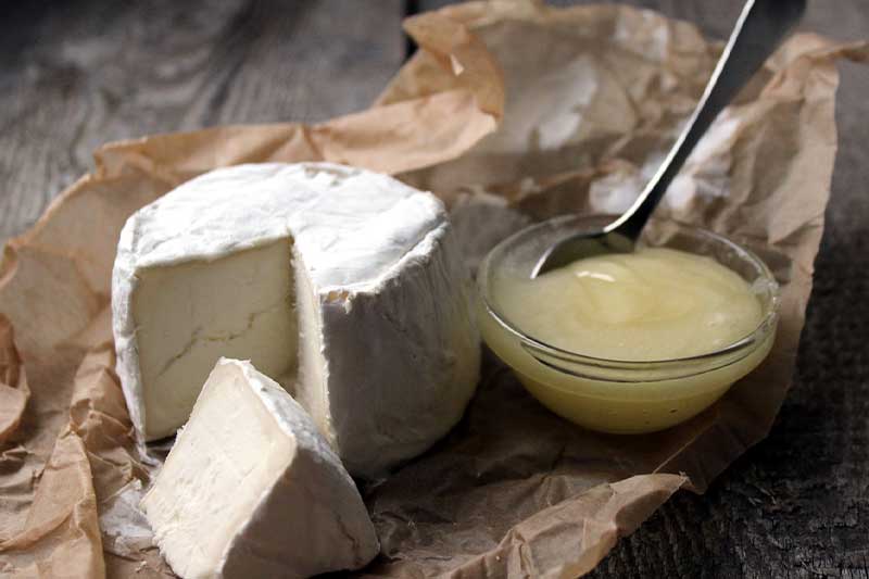 A piece of cheese and a spoon on a piece of paper.